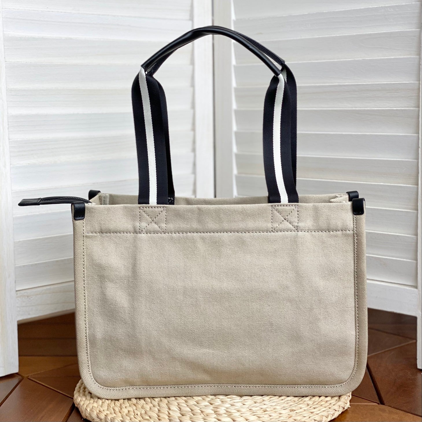 Beige canvas tote bag with sporty striped handles, bold logo print, and a zippered closure – a casual yet stylish everyday bag