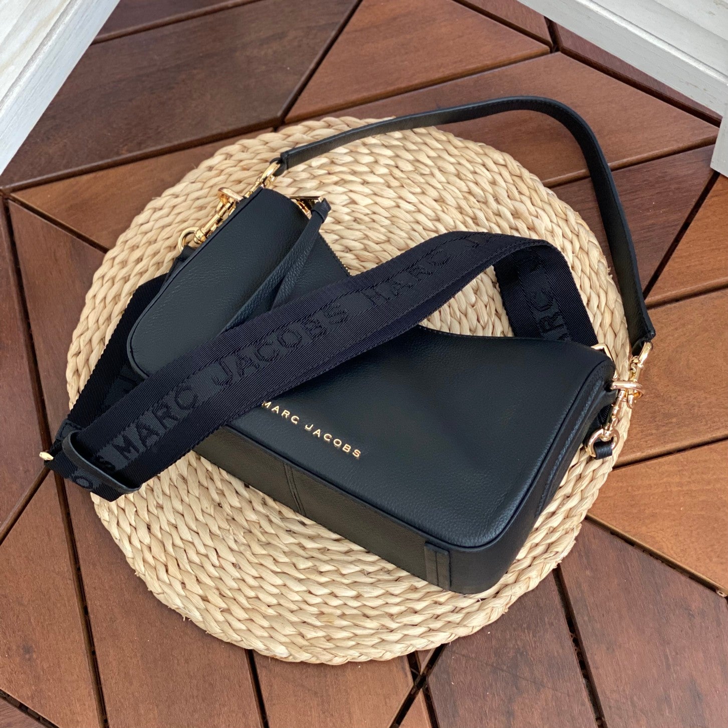 Black canvas tote bag with gold embroidered logo, khaki contrast handles, and zippered closure – a trendy yet functional everyday handbag