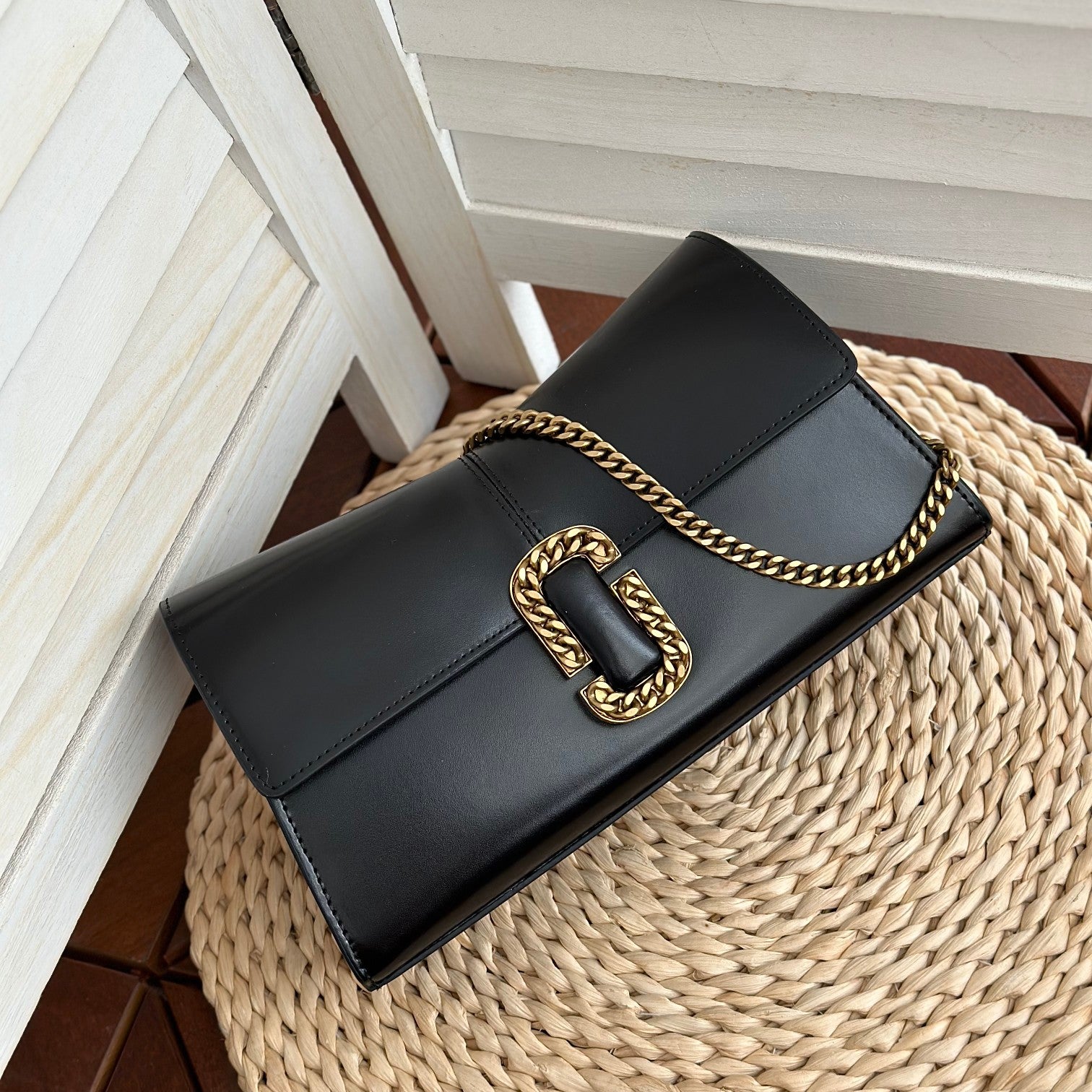  Black leather shoulder bag with gold-tone chain strap and statement buckle detail – a bold and elegant accessory for any occasion