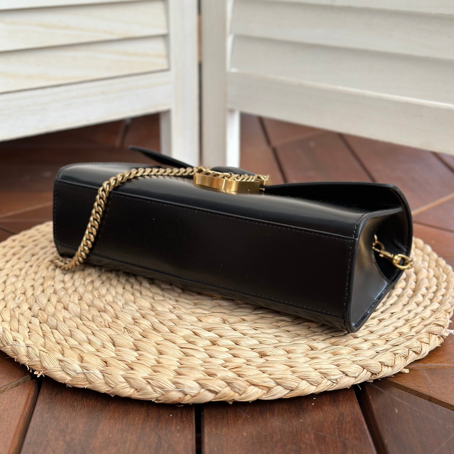  Black leather shoulder bag with gold-tone chain strap and statement buckle detail – a bold and elegant accessory for any occasion
