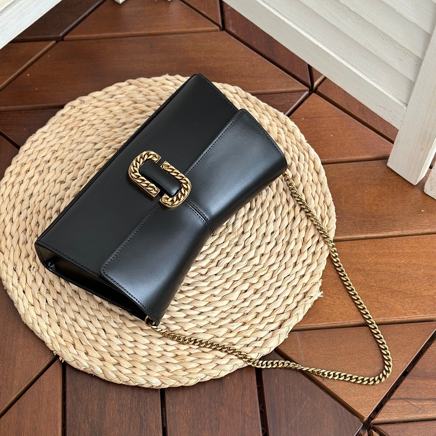  Black leather shoulder bag with gold-tone chain strap and statement buckle detail – a bold and elegant accessory for any occasion