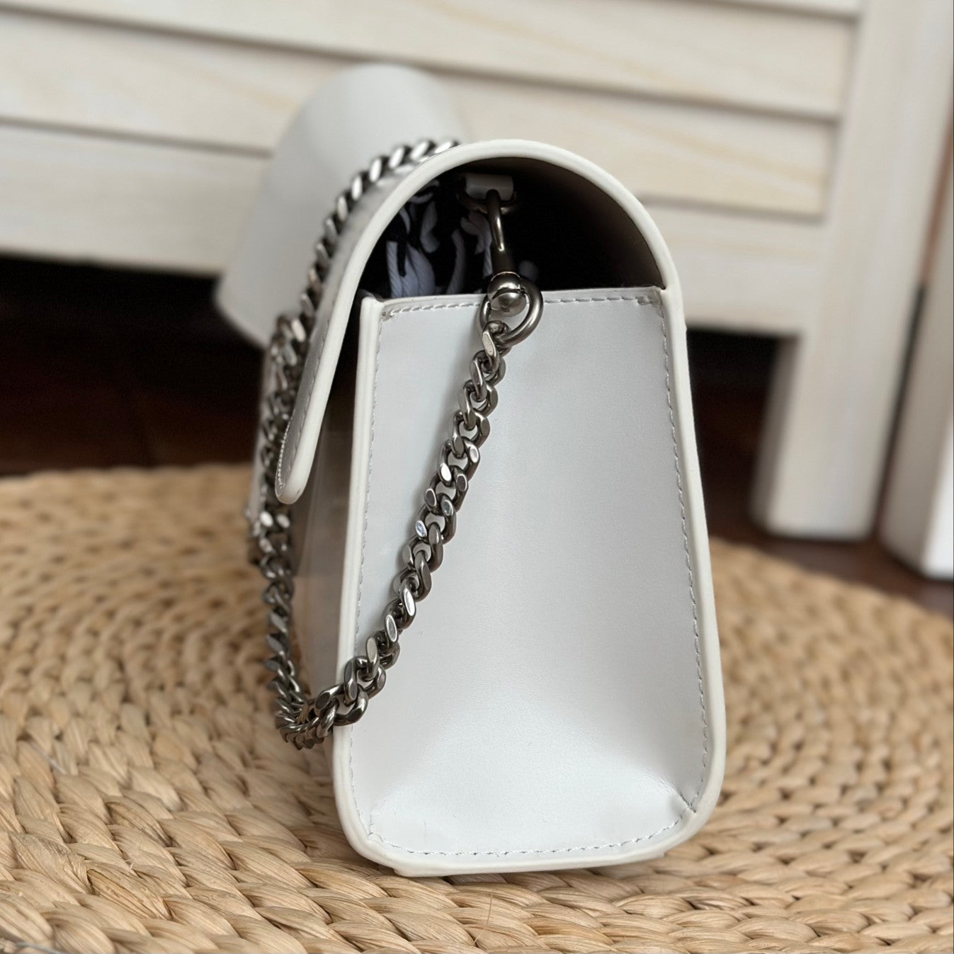 White leather shoulder bag with silver-tone chain strap and interwoven buckle – a modern luxury accessory for any occasio