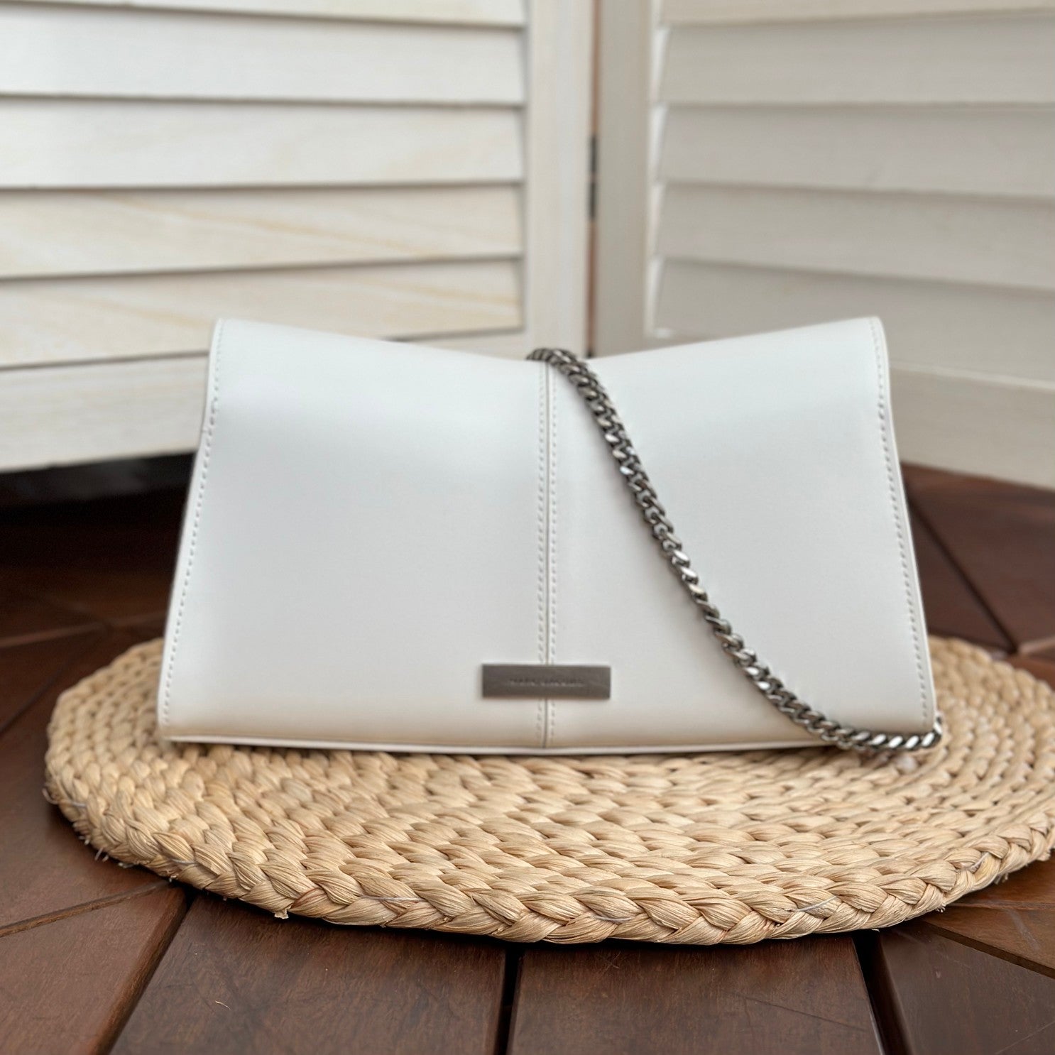 White leather shoulder bag with silver-tone chain strap and interwoven buckle – a modern luxury accessory for any occasio