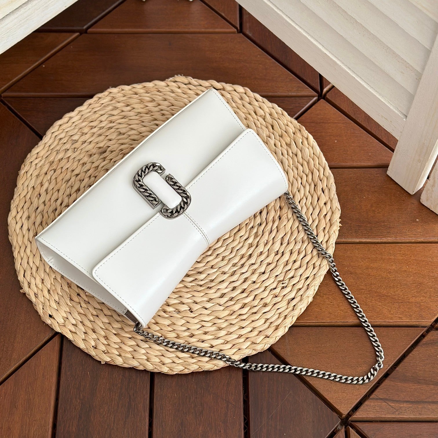 White leather shoulder bag with silver-tone chain strap and interwoven buckle – a modern luxury accessory for any occasio