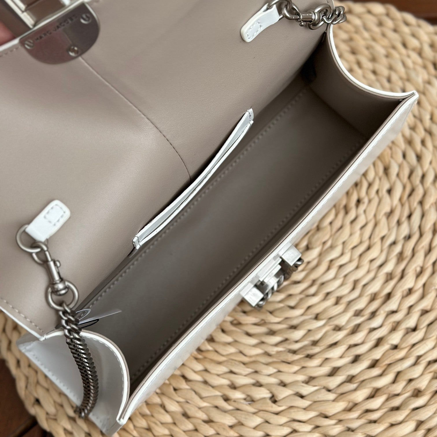 White leather shoulder bag with silver-tone chain strap and interwoven buckle – a modern luxury accessory for any occasio