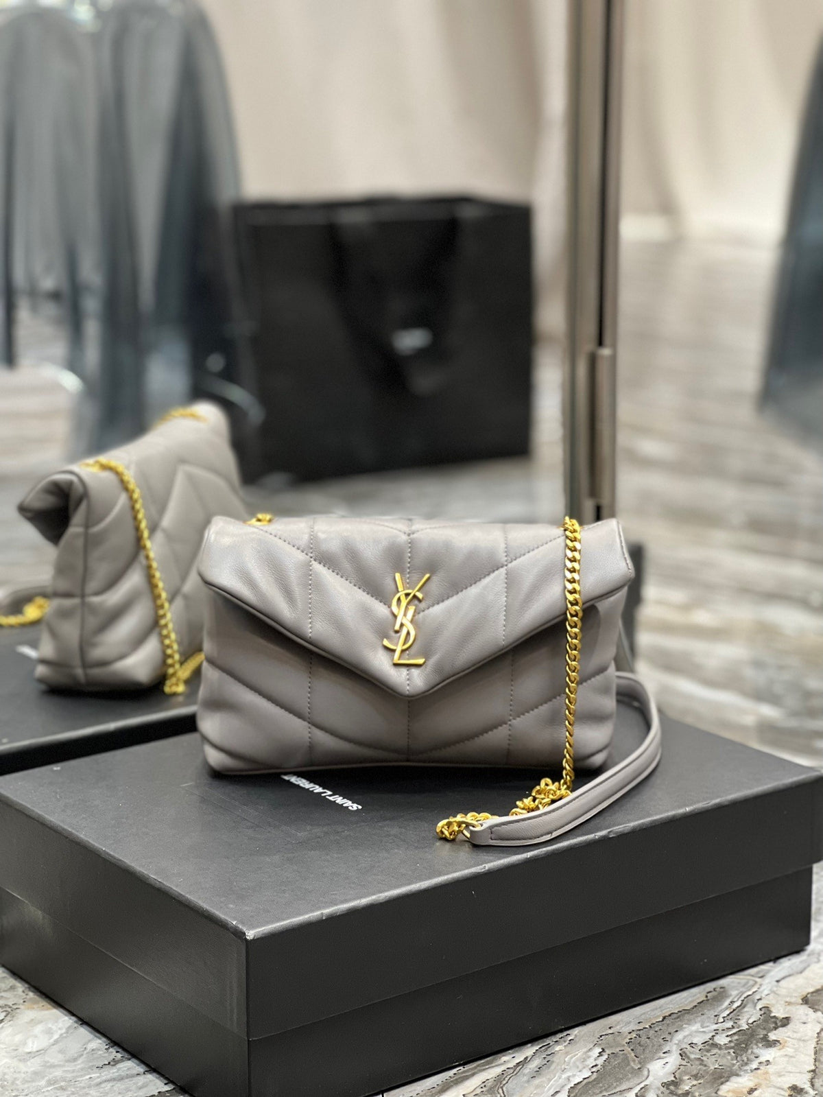  Gray quilted leather shoulder bag with gold-tone chain strap and soft, slouchy silhouette – a modern luxury accessory.