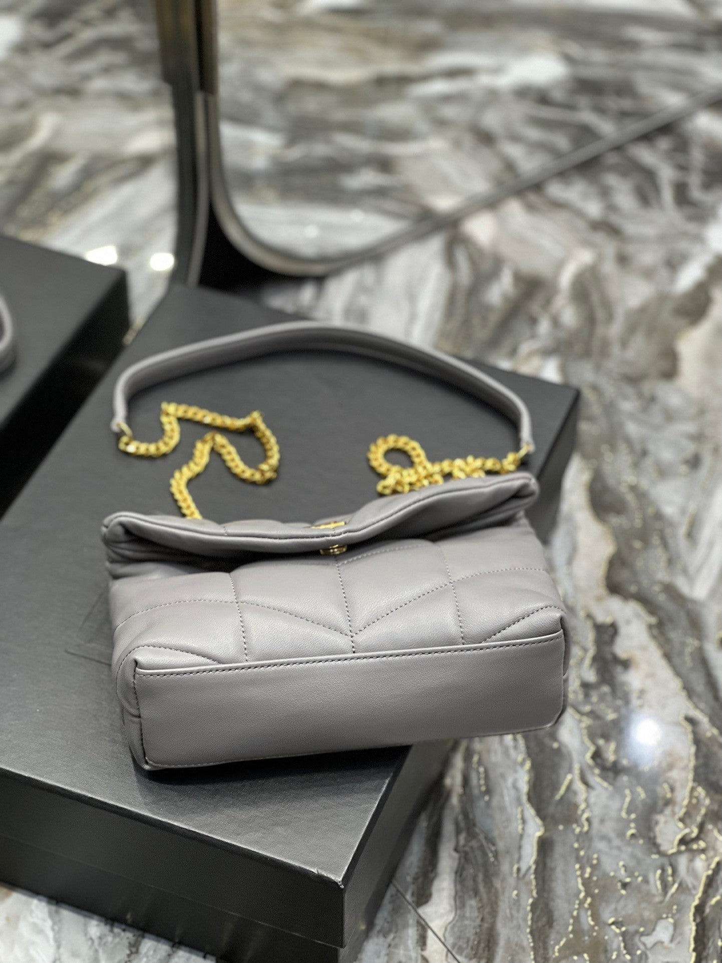  Gray quilted leather shoulder bag with gold-tone chain strap and soft, slouchy silhouette – a modern luxury accessory.
