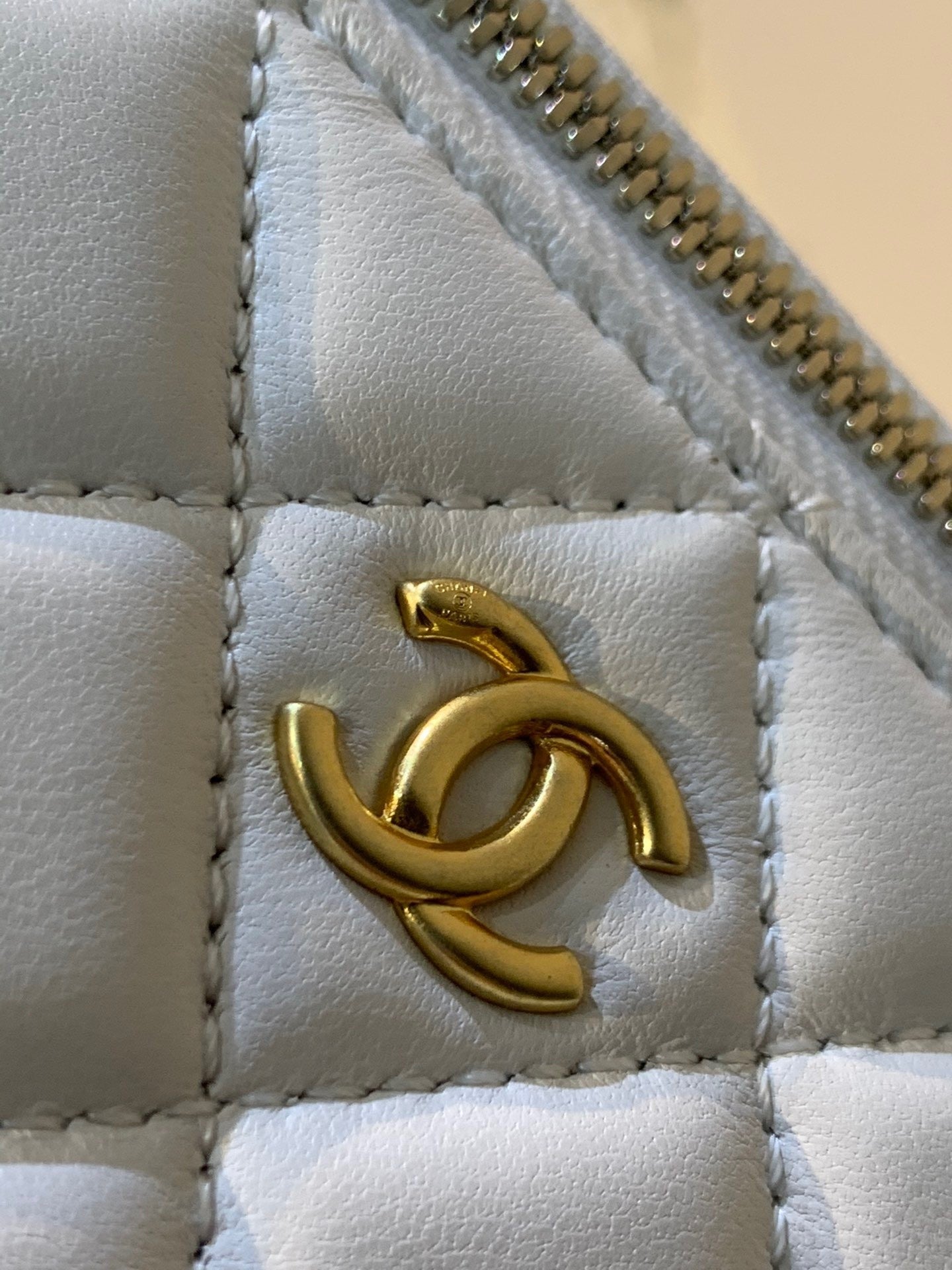 White quilted leather mini vanity bag with gold-tone chain strap and elegant structured silhouette – a must-have luxury accessory.