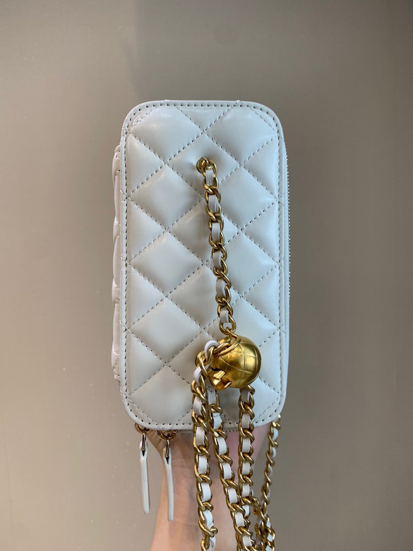 White quilted leather mini vanity bag with gold-tone chain strap and elegant structured silhouette – a must-have luxury accessory.