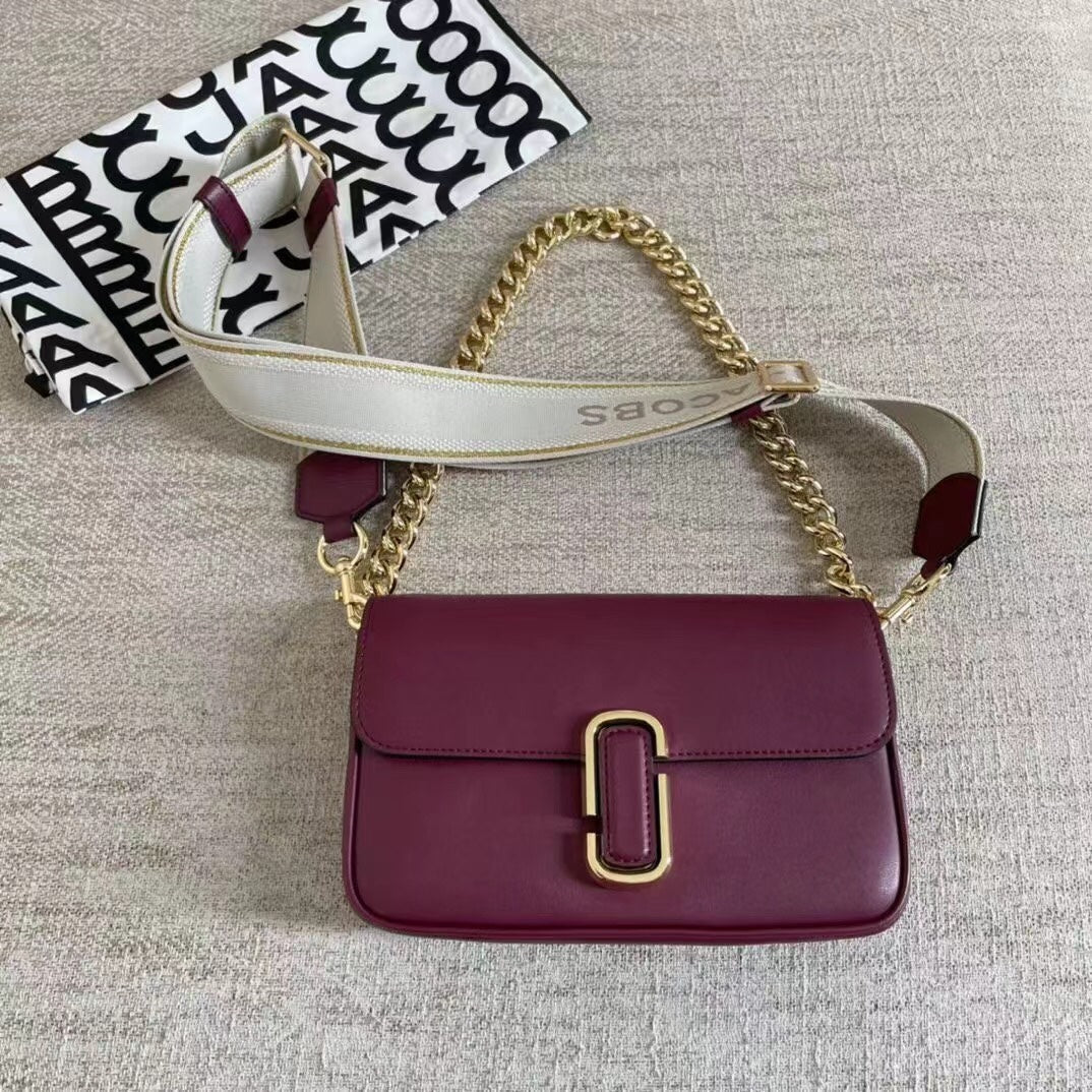 Burgundy leather shoulder bag with gold-tone chain, adjustable fabric strap, and sleek modern silhouette – a luxurious and stylish handbag