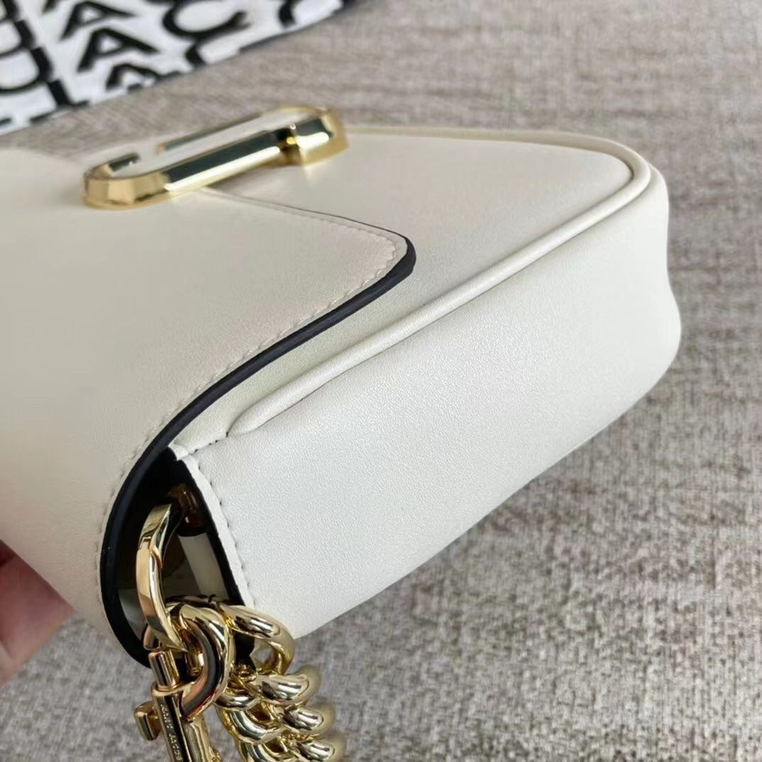 Ivory leather shoulder bag with gold-tone chain, adjustable fabric strap, and statement buckle – a modern minimalist handbag for every occasion