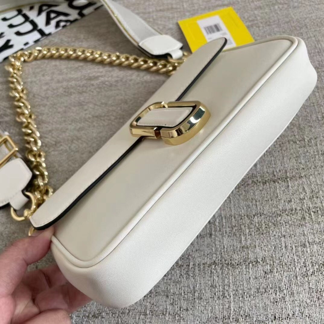 Ivory leather shoulder bag with gold-tone chain, adjustable fabric strap, and statement buckle – a modern minimalist handbag for every occasion
