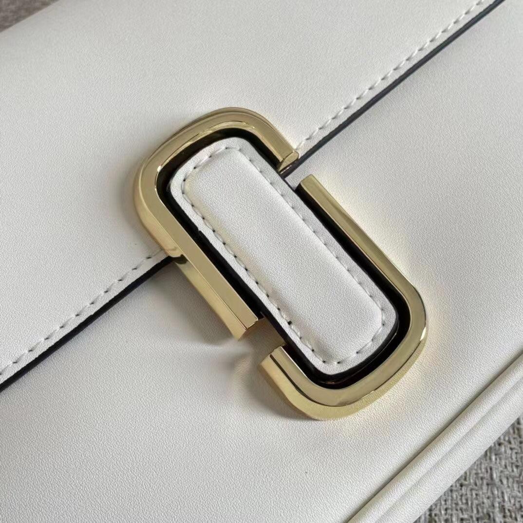 Ivory leather shoulder bag with gold-tone chain, adjustable fabric strap, and statement buckle – a modern minimalist handbag for every occasion